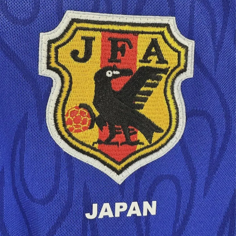 Embroidered logo with 'JFA' and a black bird on a yellow shield against a blue background
