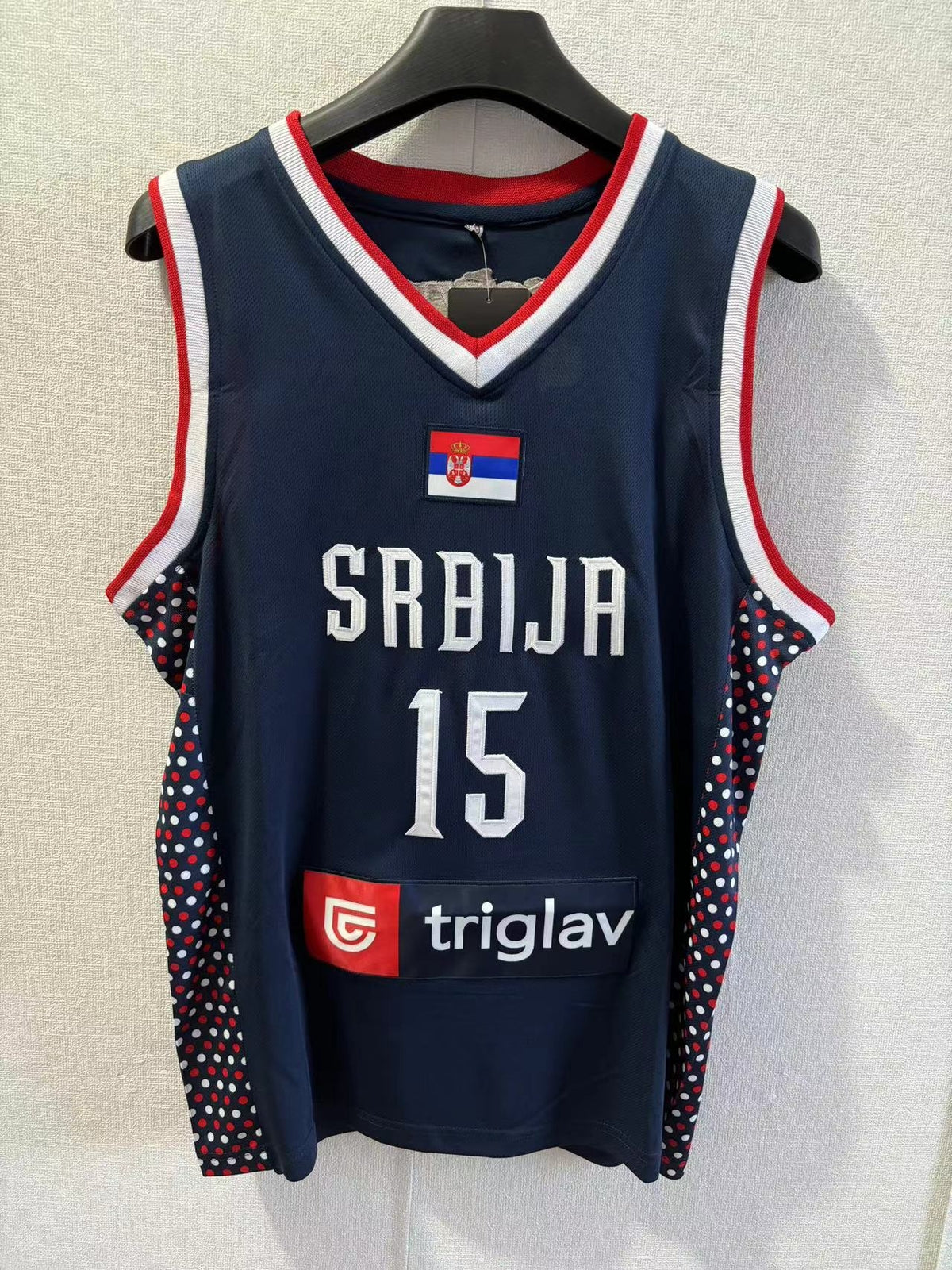 Navy basketball jersey with 'Srbija' and number '15' on a hanger against a light background